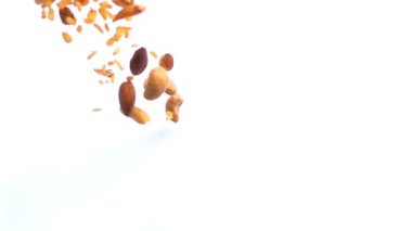 Ağır çekimde masada beyaz kağıt üzerine düşen karışık Kuruyemiş