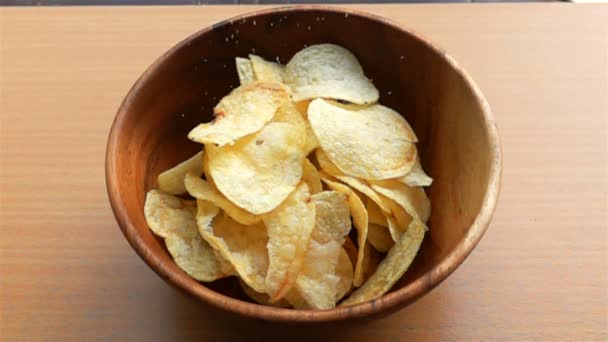 Streuen Sie Salz Zeitlupe Auf Einen Haufen Kartoffelchips Einer Holzschüssel — Stockvideo