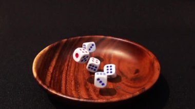 Ağır çekimde siyah arka plan üzerine ahşap kase içine zar atmak