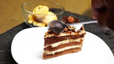 Beyaz plaka üzerinde katmanlı çikolata kek kesme ve yeme