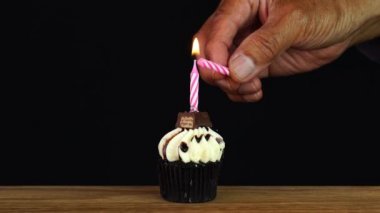 Adam ahşap bir masada Doğum günü çikolata Cupcake bir mum yaktı ve sonra üflenir