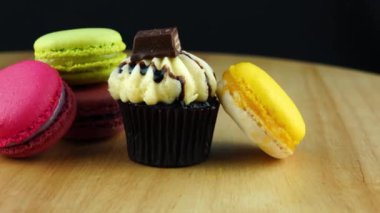 Lezzetli çikolatacupcake ve çok renkli macaroons kahverengi ahşap tahta üzerinde hareket