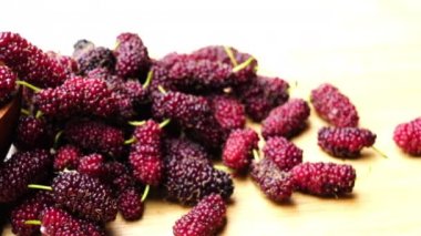 Tahta bir tahta üzerinde hareket eden ahşap bir kase taze dut yığını