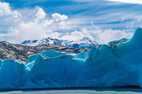 Blauwe ijsberg van de grijze gletsjer op het grijze meer en de besneeuwde berg op — Stockfoto