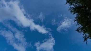 Yağmur mevsiminde mavi gökyüzünde hareket eden kararsız kabarık tüylü beyaz bulutların zaman akışı.