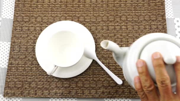 男は熱い黒コーヒーをテーブルマットの上に白いコーヒーカップに注ぐ — ストック動画