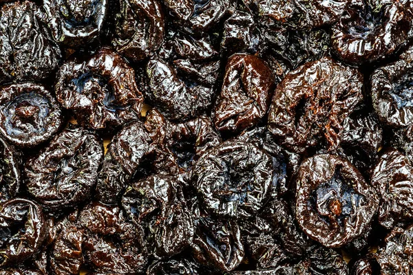 Top view of pitted prunes on wooden board. Prunes are 64% carbohydrates including dietary fiber, 2% protein, a rich source of vitamin K, and a moderate source of B vitamins and dietary minerals.