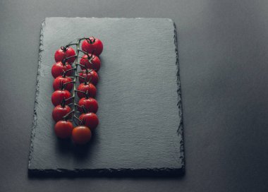 taze domates taş siyah bir arka plan üzerinde kiraz Şubesi 