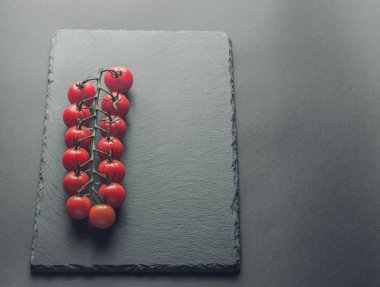 taze domates taş siyah bir arka plan üzerinde kiraz Şubesi 