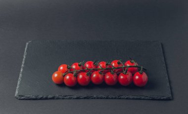 taze domates taş siyah bir arka plan üzerinde kiraz Şubesi 