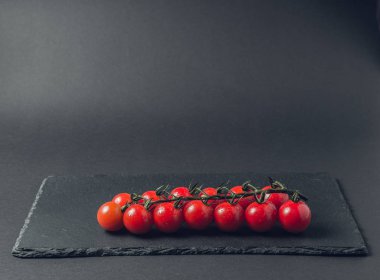 taze domates taş siyah bir arka plan üzerinde kiraz Şubesi 