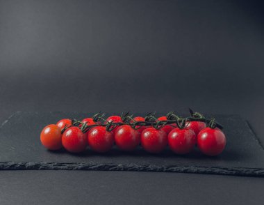 taze domates taş siyah bir arka plan üzerinde kiraz Şubesi 