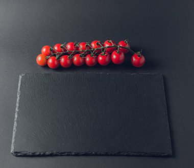 taze domates taş siyah bir arka plan üzerinde kiraz Şubesi 