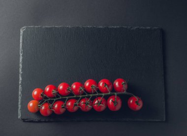 taze domates taş siyah bir arka plan üzerinde kiraz Şubesi 