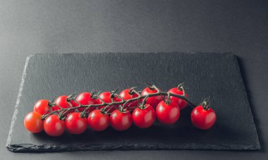 taze domates taş siyah bir arka plan üzerinde kiraz Şubesi 