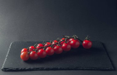 taze domates taş siyah bir arka plan üzerinde kiraz Şubesi 