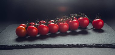 taze domates taş siyah bir arka plan üzerinde kiraz Şubesi 