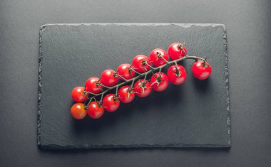 taze domates taş siyah bir arka plan üzerinde kiraz Şubesi 