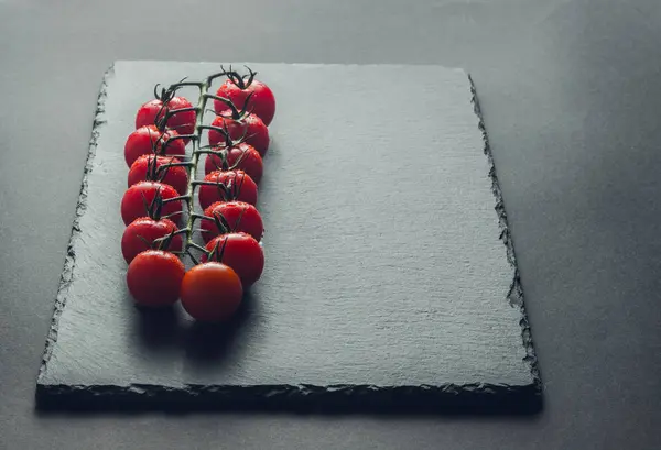 taze domates taş siyah bir arka plan üzerinde kiraz Şubesi 