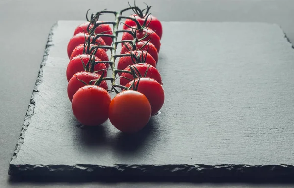 taze domates taş siyah bir arka plan üzerinde kiraz Şubesi 