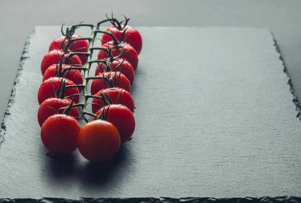taze domates taş siyah bir arka plan üzerinde kiraz Şubesi 