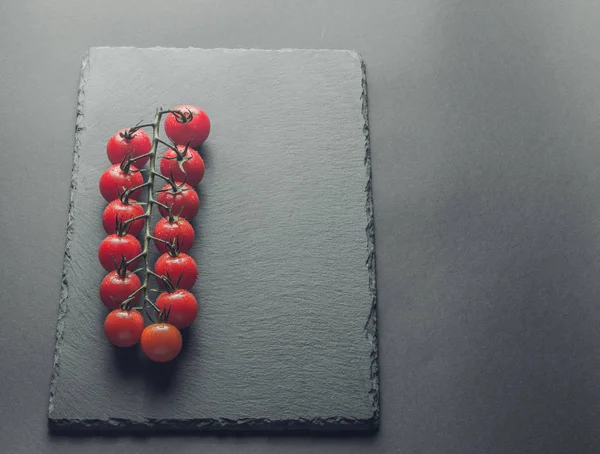 taze domates taş siyah bir arka plan üzerinde kiraz Şubesi 