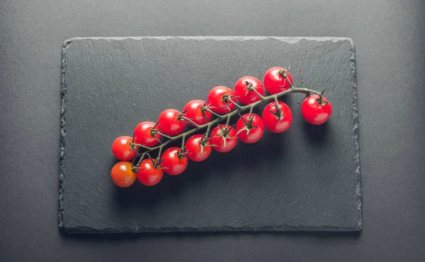 taze domates taş siyah bir arka plan üzerinde kiraz Şubesi 