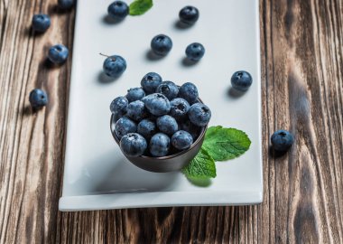 ahşap arka plan üzerinde beyaz bir tabakta nane ile yaban mersini