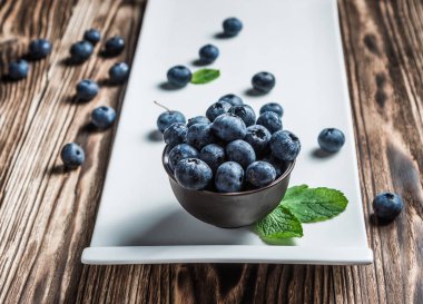 ahşap arka plan üzerinde beyaz bir tabakta nane ile yaban mersini