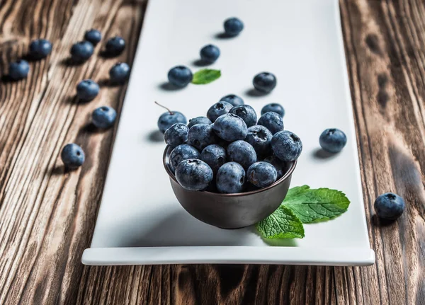 ahşap arka plan üzerinde beyaz bir tabakta nane ile yaban mersini