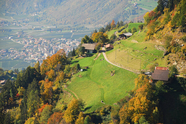 View on meadows and cottages in the italian alps near Meran, South Tyrol, Italy. In the distance the village Partschins