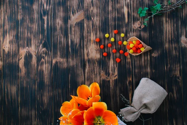 Тюльпани з цукерками у вафельному розі на дерев'яному фоні — стокове фото