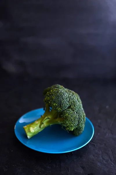 Fresh broccoli in a blue plate on a black background — Stock Photo, Image