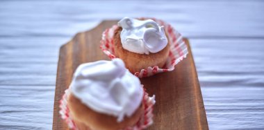 Ahşap arka plan üzerinde beyaz krema ile cupcakes
