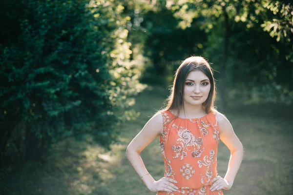 Schönes junges Mädchen in einem sommerroten Kleid in einem Park — Stockfoto