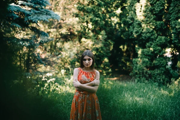 Menina bonita em um vestido vermelho de verão em um parque — Fotografia de Stock