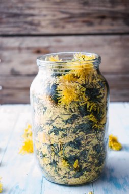 Karahindiba çiçekler ve ev yapımı bitkisel şurup hazırlamak için bal dolu bir cam kavanoz