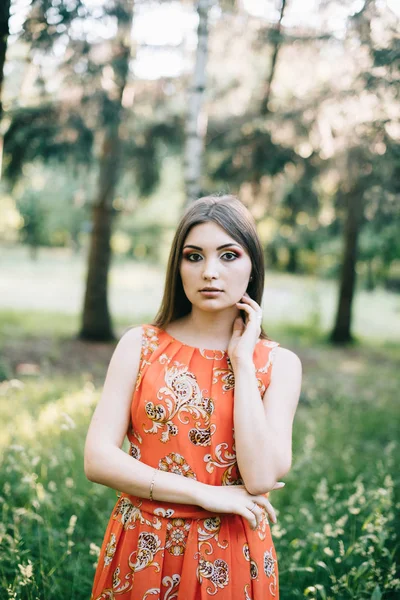 Vacker ung flicka i en röd sommar klänning i en park — Stockfoto