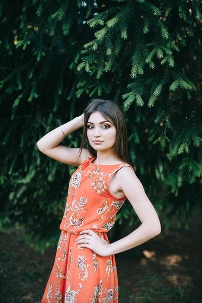 Vacker ung flicka i en röd sommar klänning i parken — Stockfoto