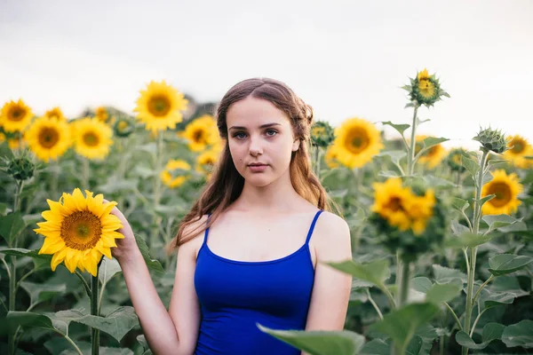 Menina bonita no campo com girassóis em shorts curtos e um colete — Fotografia de Stock