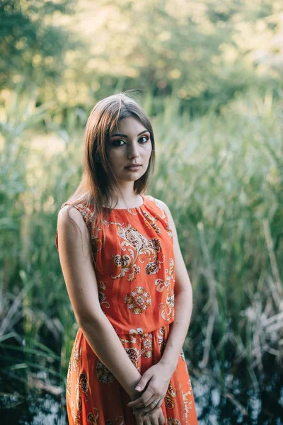 Schönes junges Mädchen in einem sommerroten Kleid im Park — Stockfoto