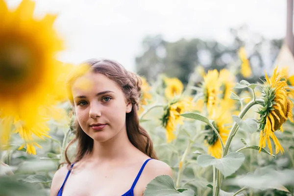 Hermosa chica en el campo con girasoles en pantalones cortos y un chaleco —  Fotos de Stock