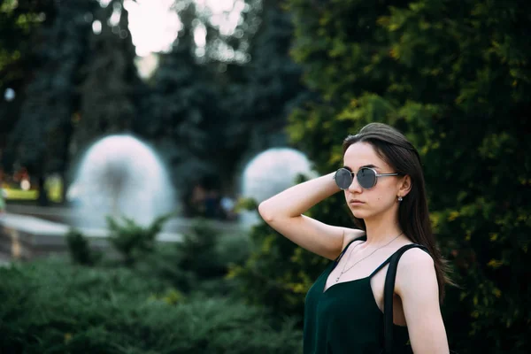 Hermosa joven en un parque en gafas de sol — Foto de Stock