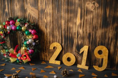 Noel çelenk ahşap koyu arka plan üzerinde altın sayılarla 2019