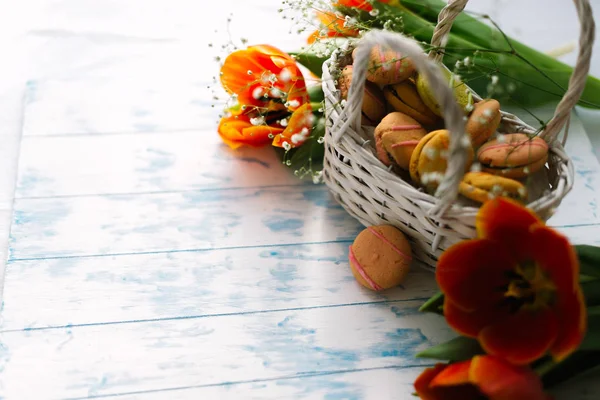 Квітучі тюльпани біля кошика з макарунами — стокове фото