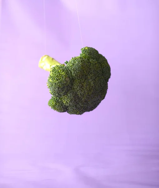 Świeże brokuły w powietrzu na fioletowym tle — Zdjęcie stockowe