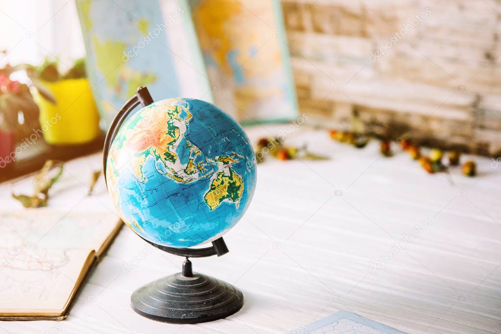 Globe on wooden white boards with a blurred background. Autumn still life