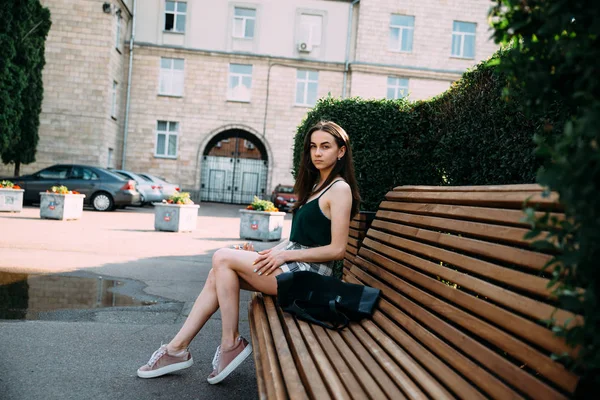 A girl in a black shirt and shorts in a park on a bench — Stock Photo, Image