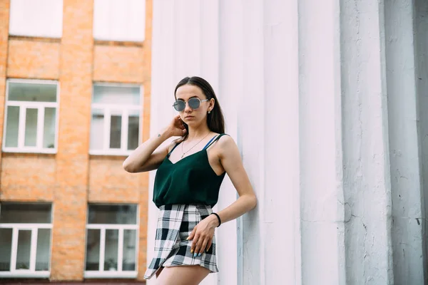 Sexy chica en gafas de sol camiseta y pantalones cortos cerca de las columnas — Foto de Stock