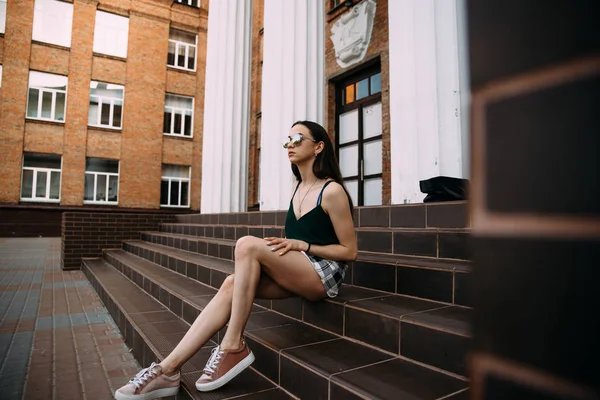 Sexy chica en gafas de sol camiseta y pantalones cortos cerca de las columnas — Foto de Stock